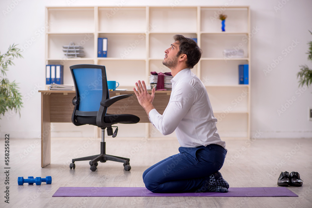 Young male employee doing sport exercises during break Young male employee doing sport exercises during break