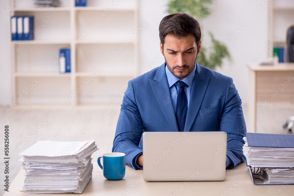 Young male employee and too much work in the office Young male employee and too much work in the office