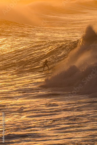 Canvas Print surfer surfing huge waves with a sunset over the sea