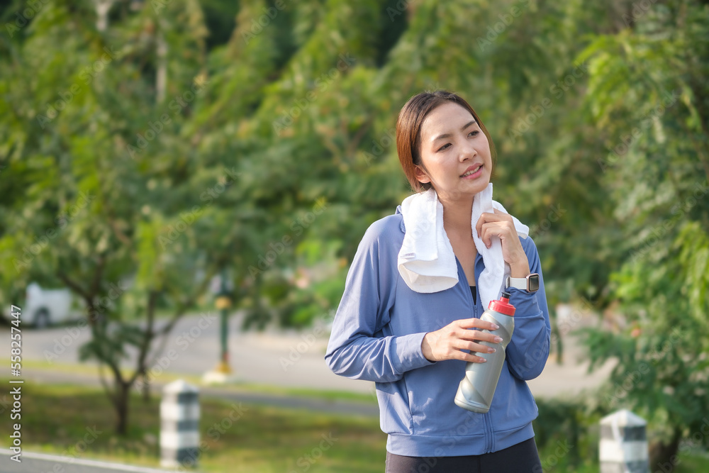 Young sporty woman taking a break and wiping sweat with a towel after running. Young sporty woman taking a break and wiping sweat with a towel after running.