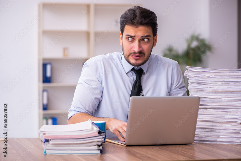 Young businessman employee unhappy with excessive work in the office Young businessman employee unhappy with excessive work in the office