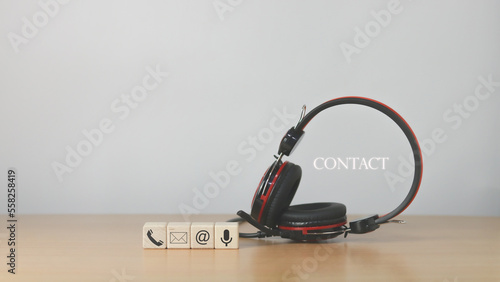 Website page, contact us or email marketing concept, customer support hotline, contact us. Wooden cubes with, email, phone, address, chat message icons on headphones