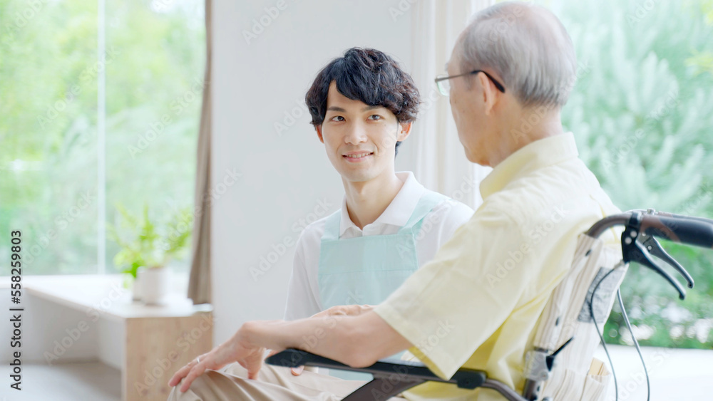 車椅子に乗った高齢者を介護する男性ヘルパー