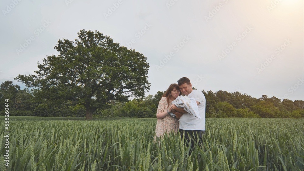 A young couple with their newborn baby in green wheat in a field. A young couple with their newborn baby in green wheat in a field.