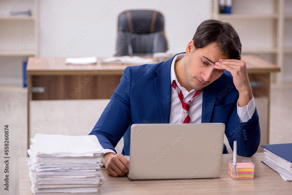 Young male employee and too much work in the office Young male employee and too much work in the office