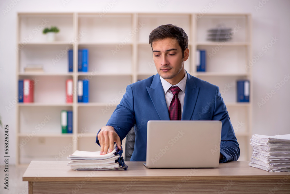 Young male employee and too much work in the office Young male employee and too much work in the office