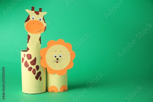 Toy giraffe and lion made from toilet paper hubs on green background, space for text. Children's handmade ideas
