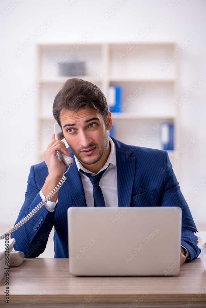 Young male employee and too much work in the office Young male employee and too much work in the office