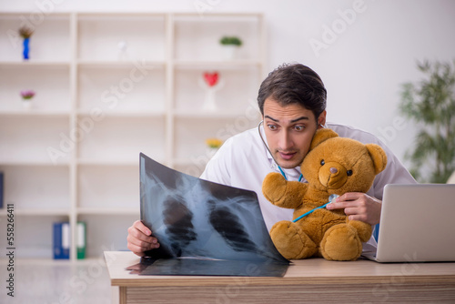 Obraz na plátně Young male doctor holding toy bear