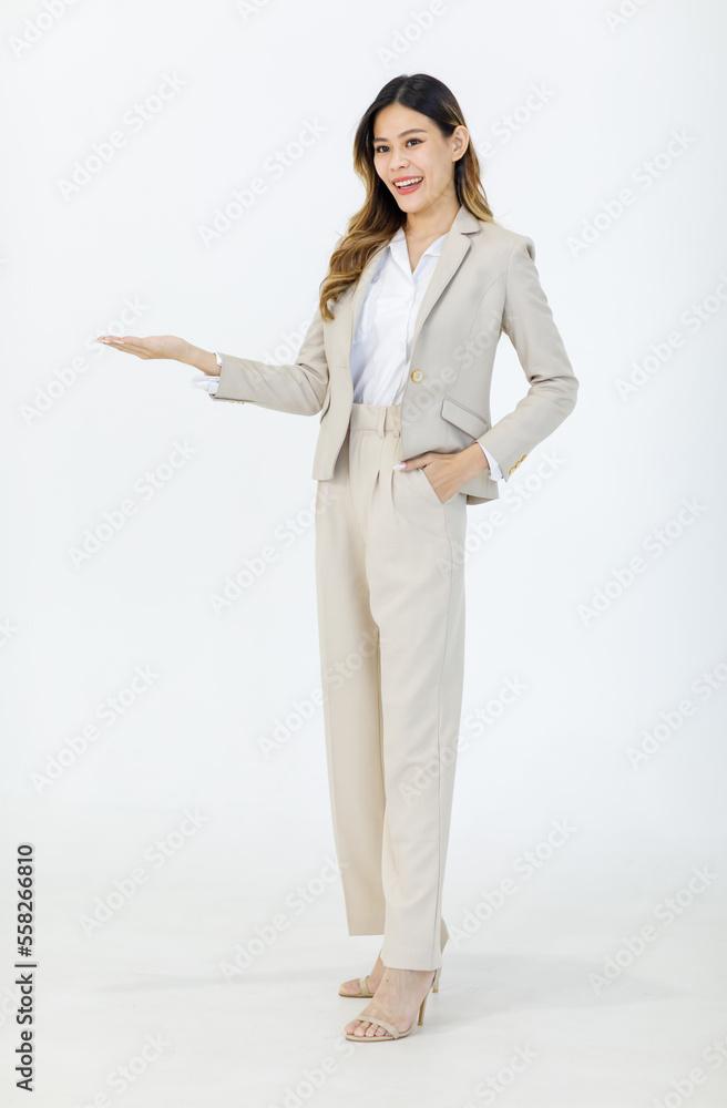 Portrait isolated cutout studio full body shot of Asian professional successful female businesswoman manager in formal suit standing smiling holding hand up presenting product on white background Portrait isolated cutout studio full body shot of Asian professional successful female businesswoman manager in formal suit standing smiling holding hand up presenting product on white background