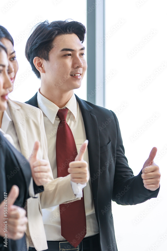Millennial Asian young professional successful male female businessmen businesswomen in formal suit standing smiling side by side smiling showing thumbs up together in company office workstation Millennial Asian young professional successful male female businessmen businesswomen in formal suit standing smiling side by side smiling showing thumbs up together in company office workstation