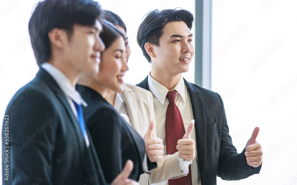 Millennial Asian young professional successful male female businessmen businesswomen in formal suit standing smiling side by side smiling showing thumbs up together in company office workstation Millennial Asian young professional successful male female businessmen businesswomen in formal suit standing smiling side by side smiling showing thumbs up together in company office workstation