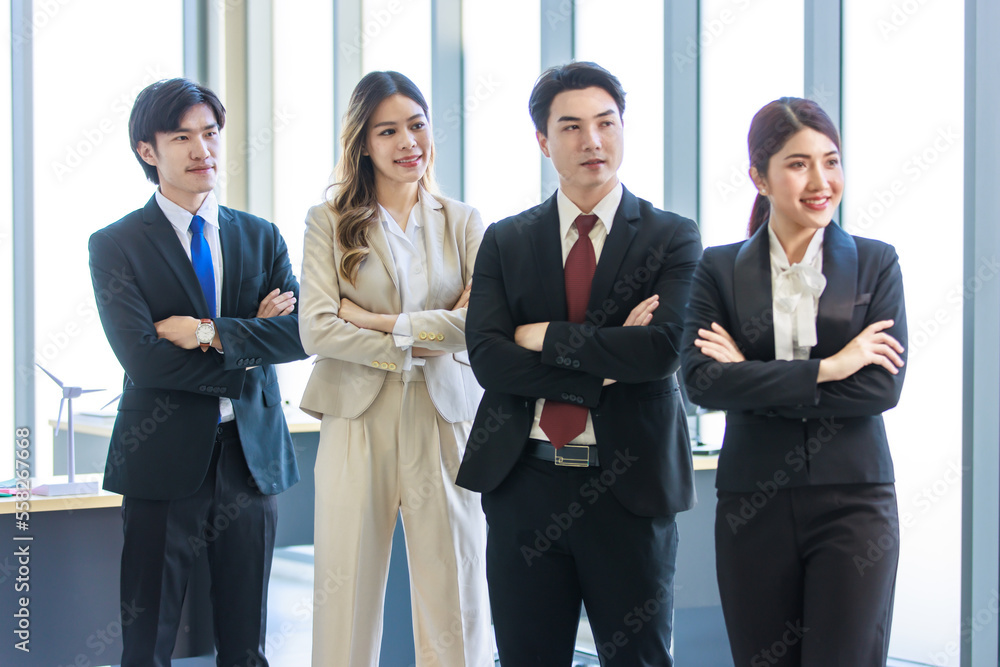 Millennial Asian young professional successful male female businessmen businesswomen in formal suit standing smiling side by side smiling in company office workstation. Millennial Asian young professional successful male female businessmen businesswomen in formal suit standing smiling side by side smiling in company office workstation.