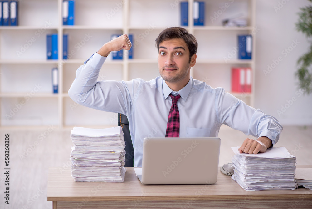 Young male employee and too much work in the office Young male employee and too much work in the office