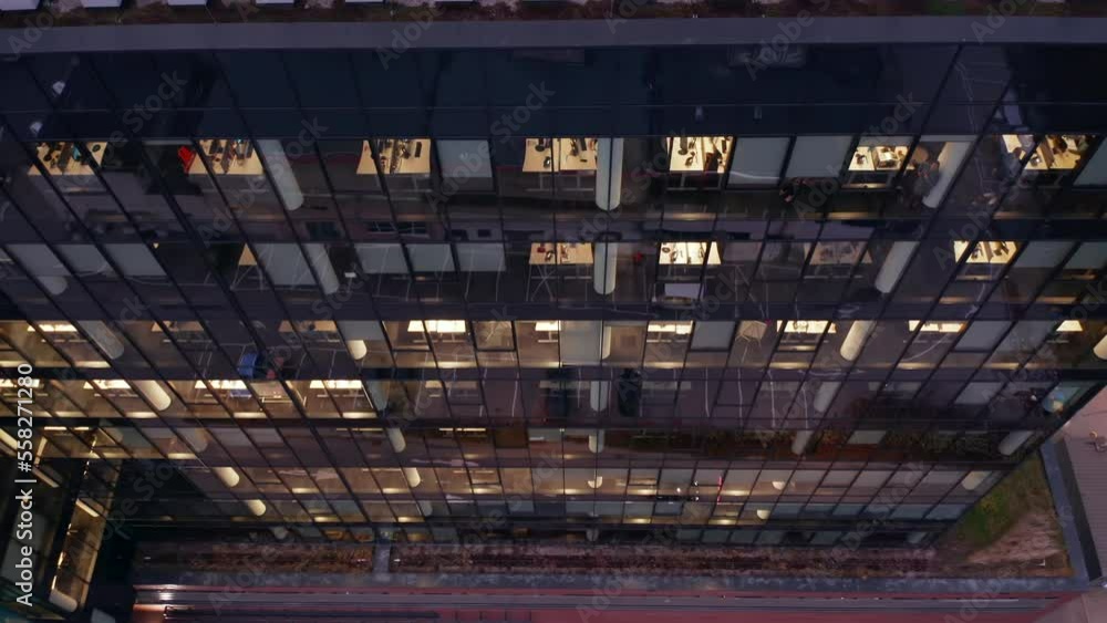 Aerial view of skyscraper windows at night. Drone shot at office windows in a skyscraper at night. Flying around the glass facade of the building with people working late. Aerial view of skyscraper windows at night. Drone shot at office windows in a skyscraper at night. Flying around the glass facade of the building with people working late.