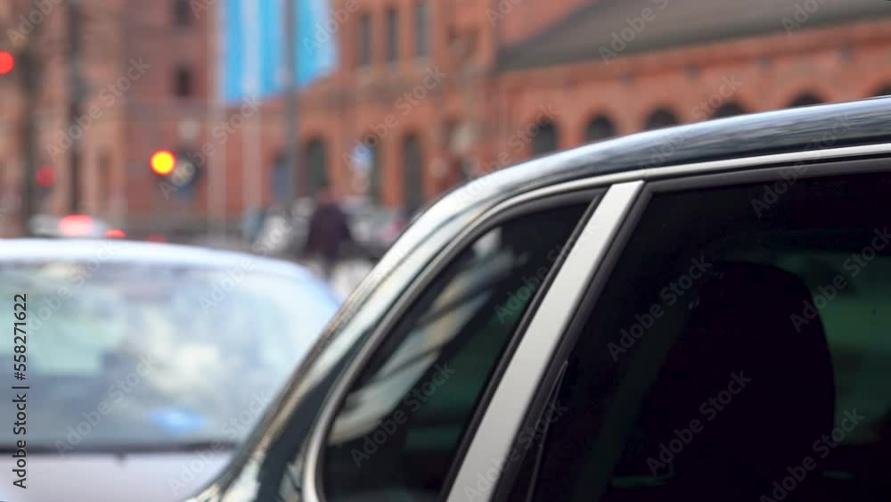 Selective focus behind a parked car, with view of flowing city traffic. Selective focus behind a parked car, with view of flowing city traffic.