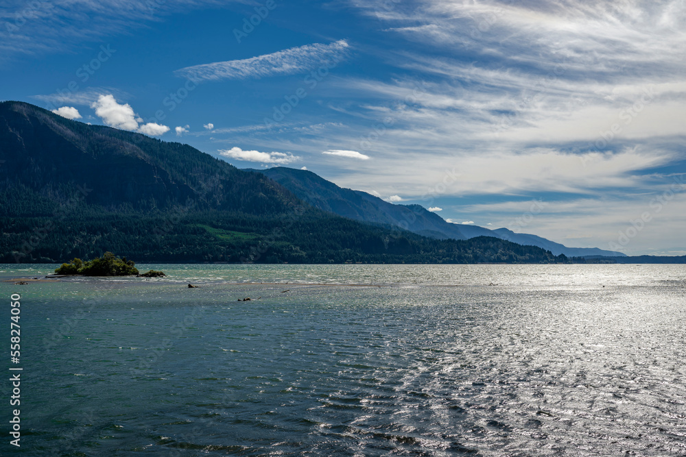 Columbia River against the backdrop of mountain ranges and cloudy sky on a sunny day in the scenic Columbia Gorge area