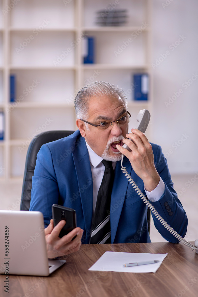 Old male employee working in the office Old male employee working in the office