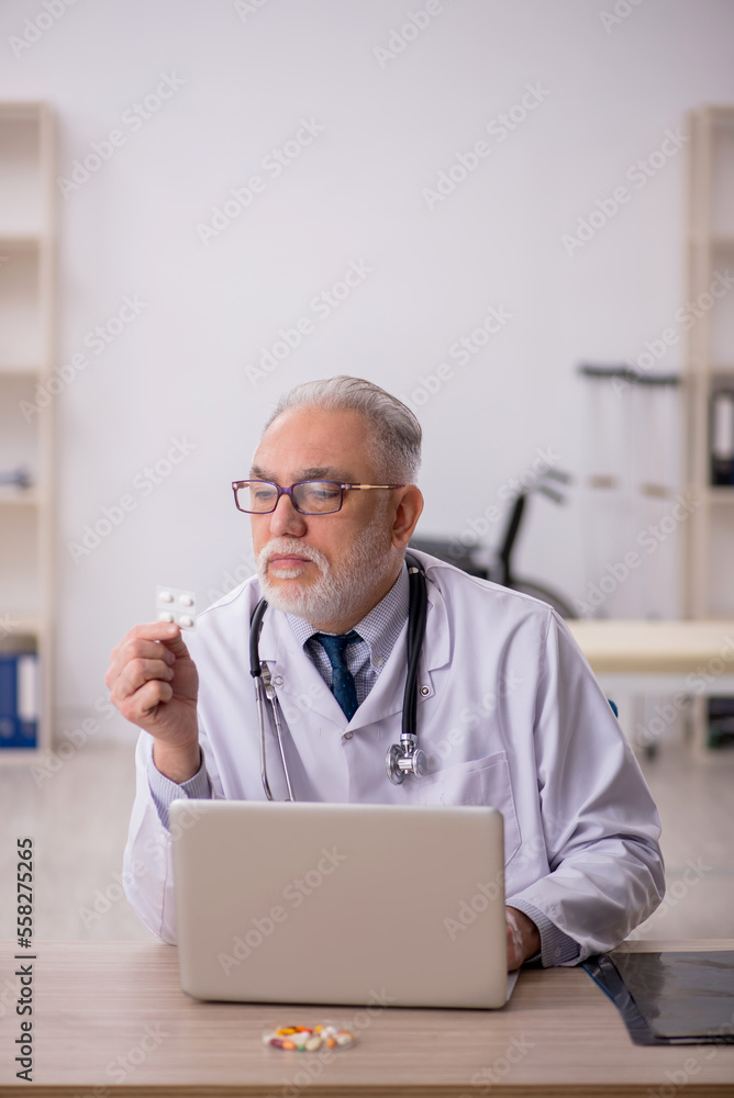 Old male doctor working in the clinic Old male doctor working in the clinic