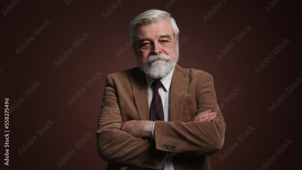 Portrait of adult, gray-haired male with a crossed arms on his chest. Close-up shot of a serious, concerned senior looking upset. High quality 4k footage