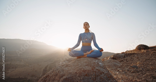 Fit girl doing lotus pose. Young athletic woman meditating in mountains  training and relaxing during sunrise - active lifestyle  zen concept 