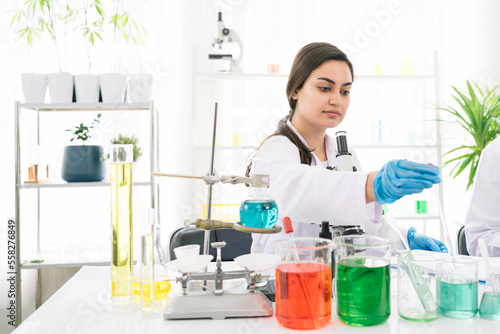 Middle East woman scientist researcher use a lab dropper to drip a substance into a test tube for analysis of liquids in the lab. Scientist working with a dropper and a test tube.