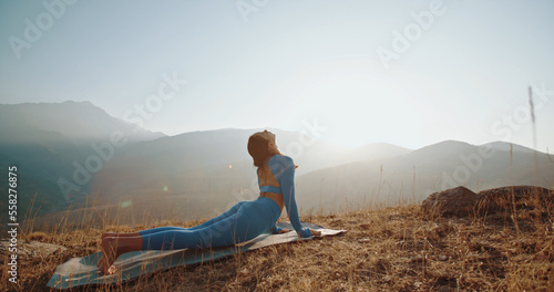 Yoga session in mountains. Young athletic girl training in cliffy mountains during sunrise  doing various yoga poses - healthy lifestyle concept 