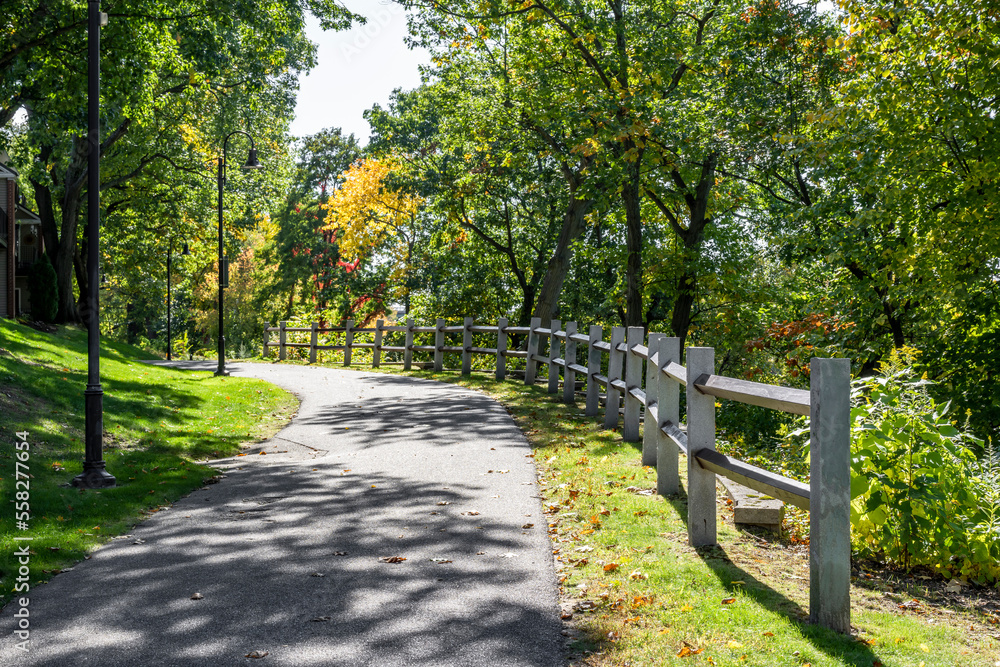 Pedestrian path with a wooden fence on the alley with autumn trees and lighting lanterns Pedestrian path with a wooden fence on the alley with autumn trees and lighting lanterns