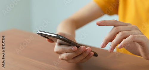 Hand holding smartphone with using social media on internet on table.
