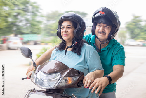 Happy senior indian woman wearing helmet learn to ride motor scooter form her husband. Closeup
