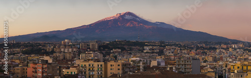 Snow covered Mount Etna volcano and Catania city center at sunset, from vantage point in Sicily, Italy