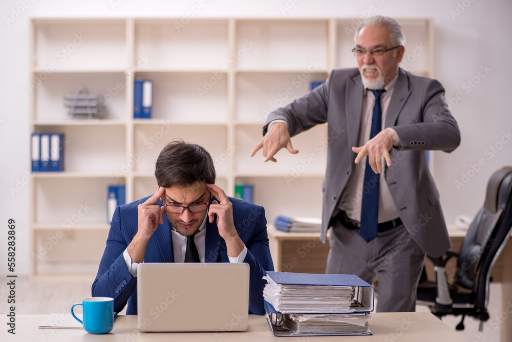 Old male boss and young male employee in the office Old male boss and young male employee in the office