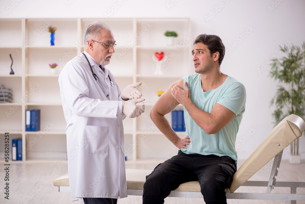 Obraz premium Young male patient visiting old male doctor in vaccination conce