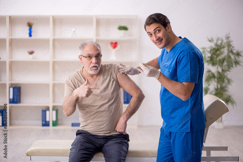 Fototapeta premium Old male patient visiting young male doctor in vaccination conce