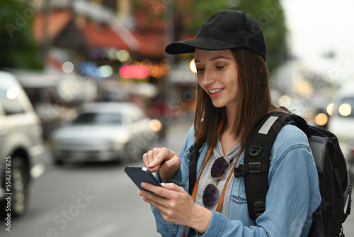 Smiling young hipster female traveler searching direction on smart phone. Life, people, travel and technology concept