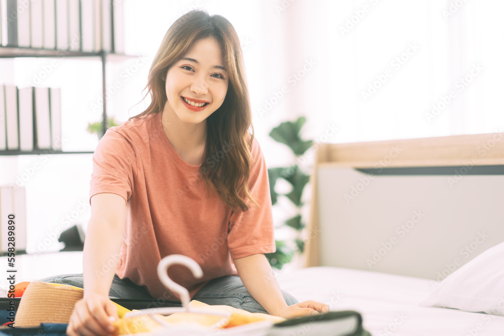 Portrait of young adult southeast asian dyed hair woman packing backpack for travel Portrait of young adult southeast asian dyed hair woman packing backpack for travel