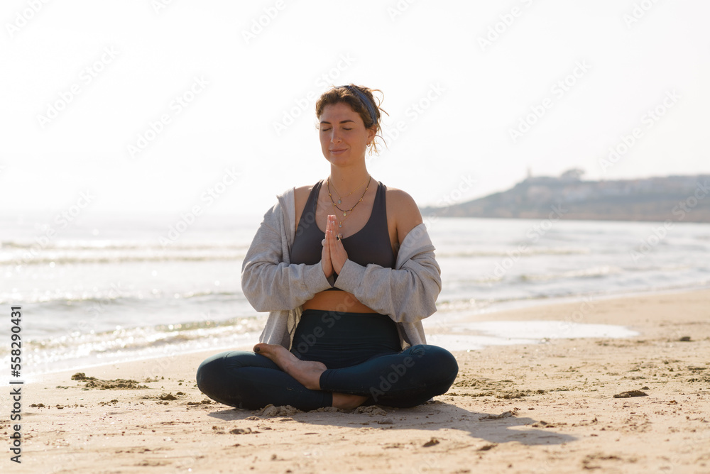 young woman does yoga on the beach