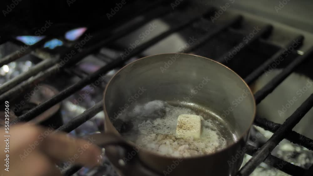 Adding spice to frying onion and butter in metal pot on gas stove, close up Adding spice to frying onion and butter in metal pot on gas stove, close up