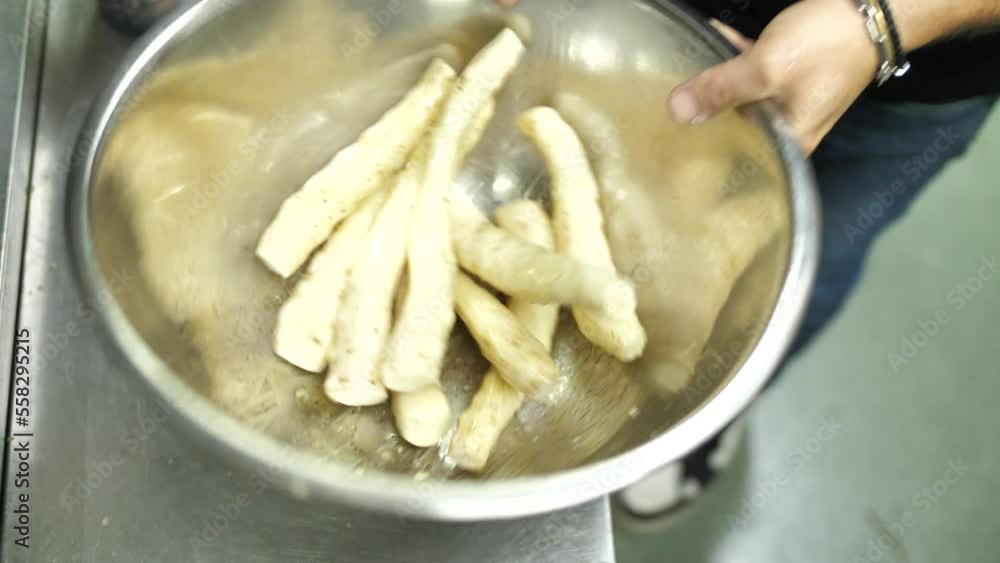 Chef mixing fresh peeled topinambur with oil and spices in metal bowl, close up Chef mixing fresh peeled topinambur with oil and spices in metal bowl, close up