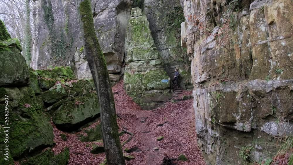 Man walking between Huge Rock Formations and giving break and drinking coffee in Mullerthal Hiking Trail in Luxembourg - Camera on front Man walking between Huge Rock Formations and giving break and drinking coffee in Mullerthal Hiking Trail in Luxembourg - Camera on front