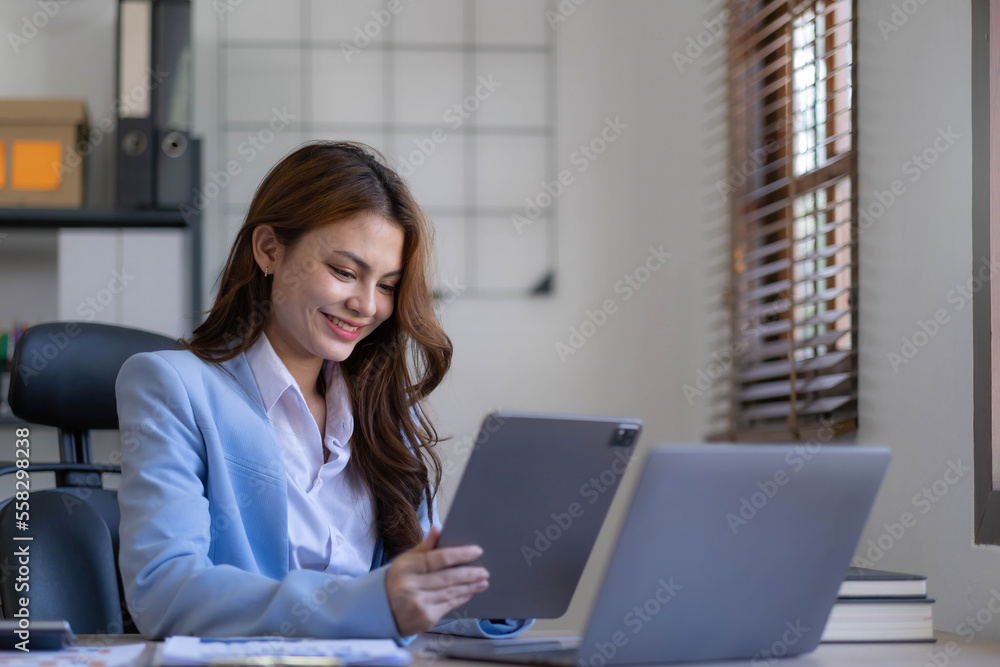 Portrait of smiling business asian woman using smartphone while sitting at workplace. Portrait of smiling business asian woman using smartphone while sitting at workplace.