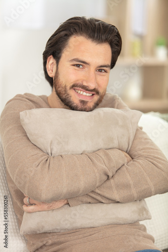 vertical shot of a young man hugging a pillow