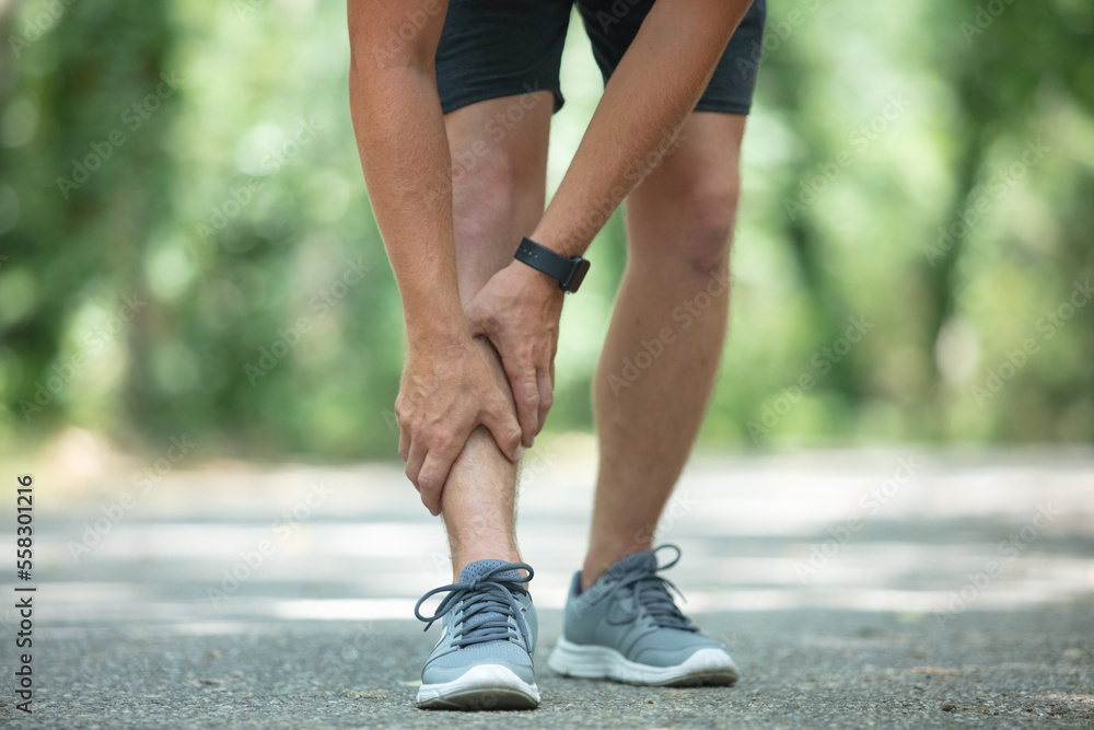 young fit man holding knee with hands in pain young fit man holding knee with hands in pain