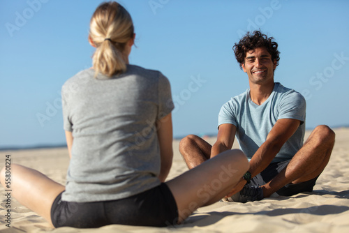 couple making yoga exercises sitting on beach outdoors
