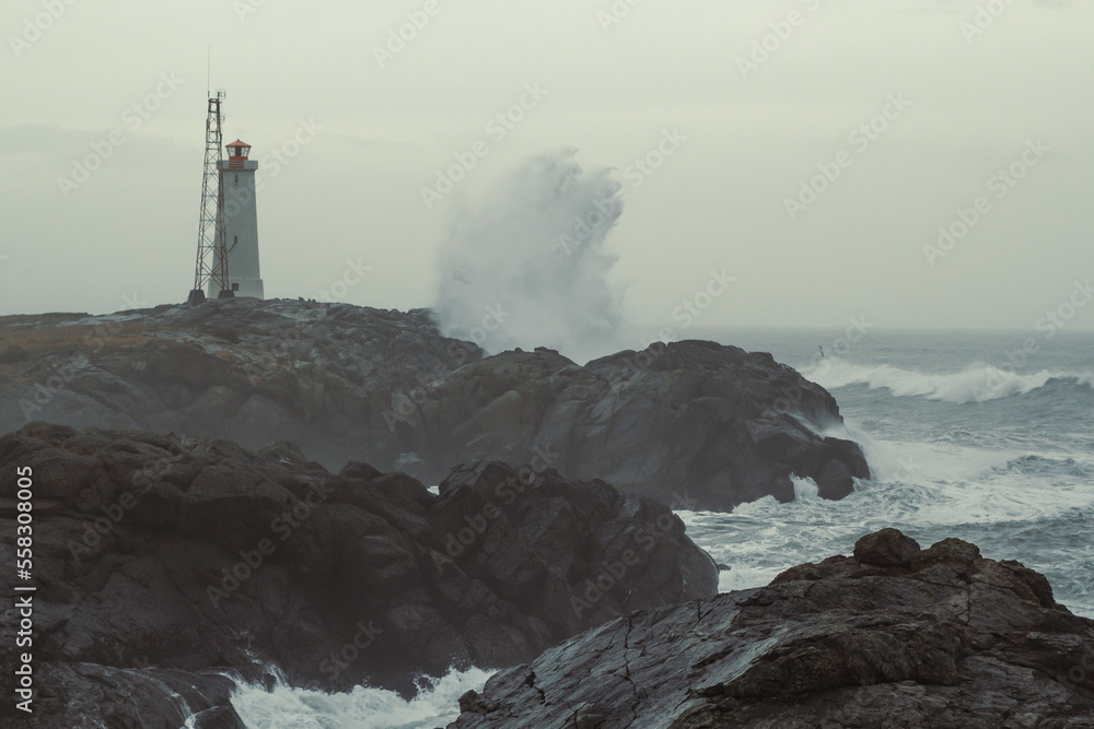 Lighthouse on rocky coast at storm landscape photo. Beautiful nature scenery photography with grey sky on background. Idyllic scene. High quality picture for wallpaper, travel blog, magazine, article