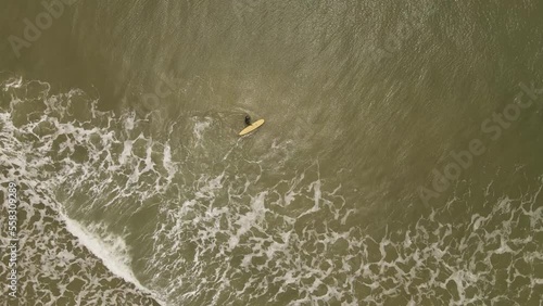 a male surfer entering the surf of the Atlantic Ocean with his board at La Pedrera Beach in Uruguay