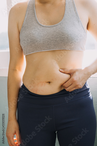 Beautiful fat woman with tape measure She uses her hand to squeeze the excess fat that is isolated on a white background. She wants to lose weight, the concept of surgery and break down fat under the