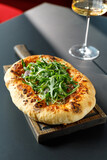 Napoli pizza with herbs on wooden cutting board served in restaurant with wine