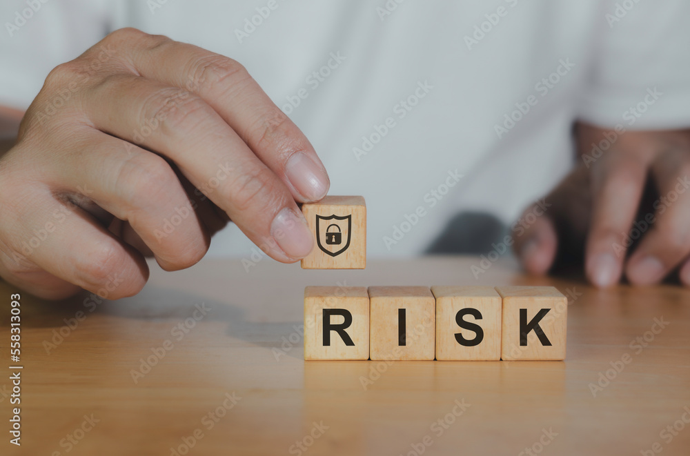 Naklejka premium Closeup wooden block written RISK icon for management concept. Hand of business choosing shield icon for protect bussiness and successful winner concept.