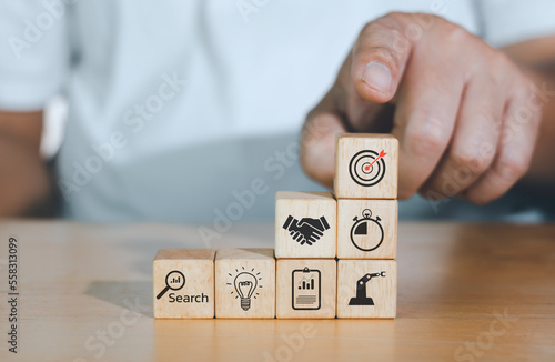 Concept of business strategy or e-commerce with shopping icons on wooden cubes against blue background. Business achievement goal and growth success objective concept.